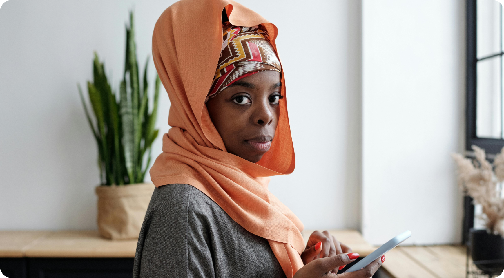 Woman wearing a headscarf holding a phone